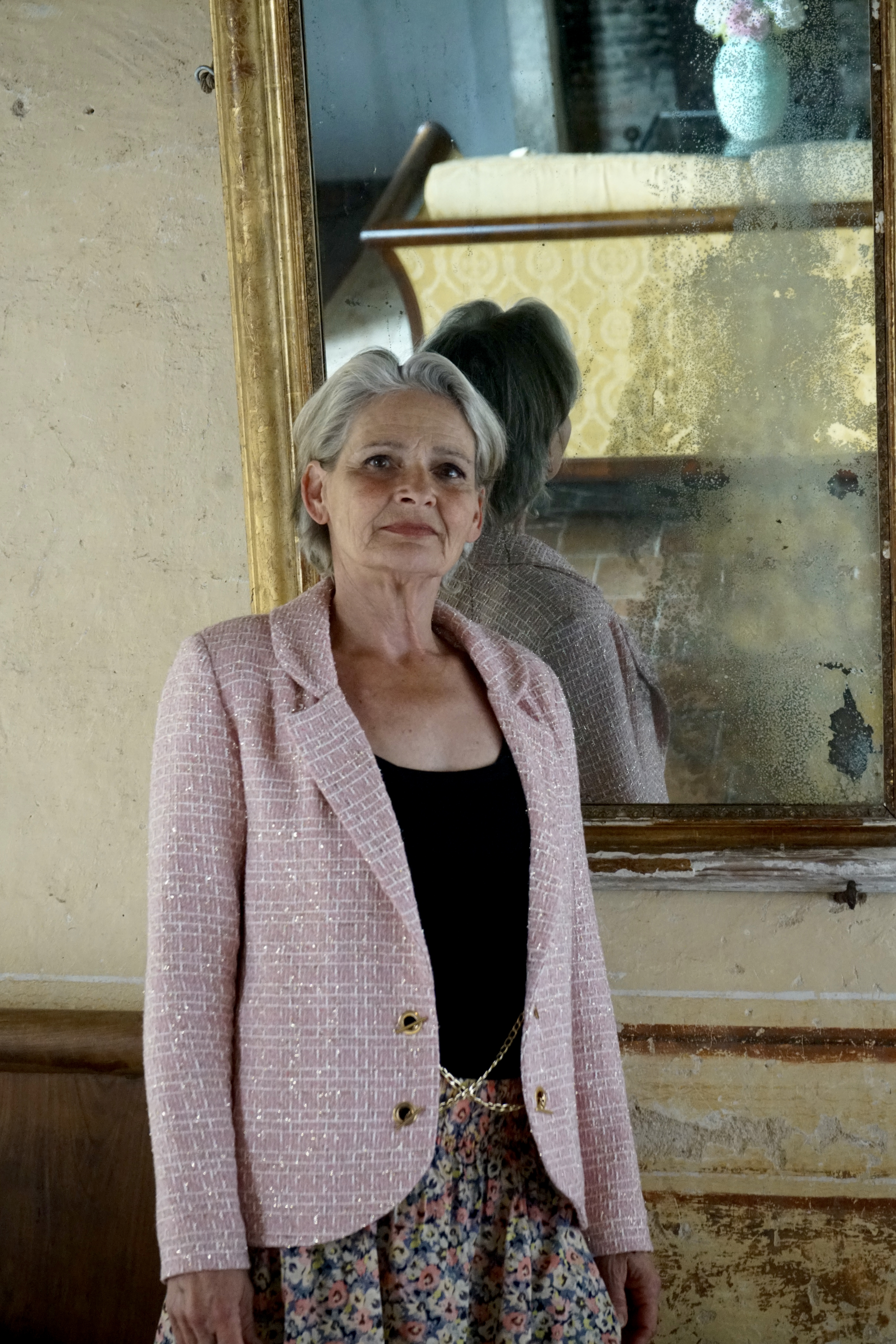 Vue de face du mannequin portant une veste tissée rose, avec un miroir derrière